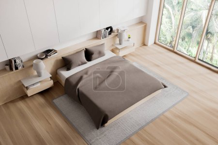Foto de Vista superior del interior del dormitorio blanco con cama y mesita de noche con decoración, alfombra en suelo de madera. Esquina de dormir con ventana panorámica en los trópicos. Renderizado 3D - Imagen libre de derechos