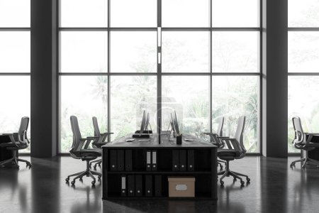 Photo for Dark stylish office interior with pc computers on desk in row, drawer with folders. Minimalist workspace with technology, furniture and panoramic window on tropics. 3D rendering - Royalty Free Image