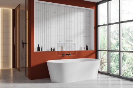 Photo for Corner of modern bathroom with orange and white tiled walls, concrete floor, comfortable white bathtub standing near window with tropical view and shower with glass door. 3d rendering - Royalty Free Image