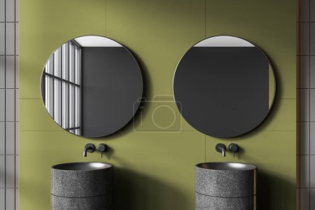Foto de Interior de un elegante cuarto de baño con paredes de baldosas de color verde oscuro y gris y cómodo lavabo doble gris con dos espejos redondos colgando por encima de ella. renderizado 3d - Imagen libre de derechos