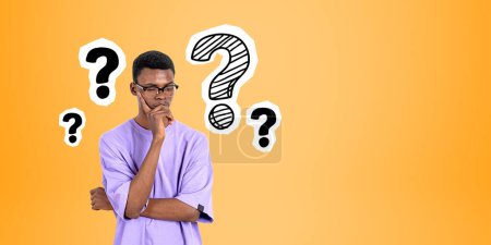 Photo for Portrait of thoughtful African man college student wearing glasses standing over orange copy space background with question marks drawn on it. Concept of choice, career and bright ideas - Royalty Free Image