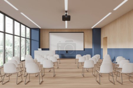 Téléchargez les photos : Intérieur de salle de conférence moderne ou salle de classe d'université avec des murs bleus et en bois, plancher en bois, rangées de chaises blanches, bureau haut-parleur blanc avec ordinateur et écran de projection maquette. Rendu 3d - en image libre de droit
