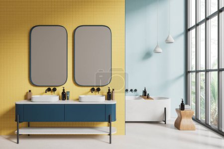 Téléchargez les photos : Intérieur de salle de bain d'hôtel jaune et bleu avec double lavabo et miroir, cloison et baignoire avec tabouret et accessoires. Fenêtre panoramique sur les tropiques. rendu 3D - en image libre de droit