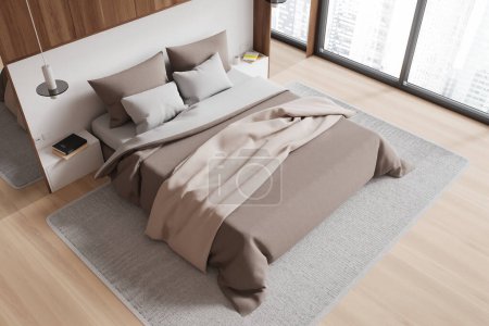 Foto de Vista superior del interior del dormitorio con cama y ropa de cama beige, alfombra en el suelo de madera. Elegante rincón relajante con diseño minimalista y ventana panorámica en rascacielos. Renderizado 3D - Imagen libre de derechos