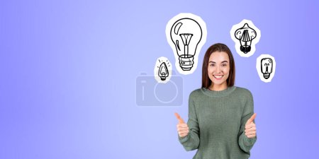 Photo for Portrait of smiling young woman college student showing thumb up gestures standing over purple copy space background with light bulbs drawn on it. Concept of bright idea and brainstorming - Royalty Free Image
