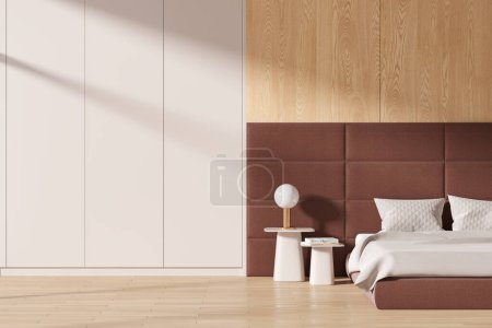 Foto de Cama interior beige y de madera del dormitorio del hotel, mesita de noche con libros y lámpara, suelo de madera y sombra abstracta. Acogedor dormitorio con pared de acento y armario. Renderizado 3D - Imagen libre de derechos