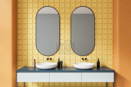 Foto de Interior luminoso baño de azulejos con doble lavabo y espejos ovalados, tocador minimalista con accesorios. Espacio de baño con pared de azulejos amarillos en apartamento de lujo. Renderizado 3D - Imagen libre de derechos