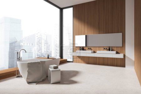 Téléchargez les photos : Coin de la salle de bain moderne avec des murs blancs et en bois, sol en béton, baignoire blanche confortable debout près de la fenêtre panoramique et double lavabo avec un long miroir. Rendu 3d - en image libre de droit