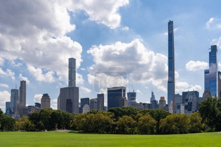 Téléchargez les photos : Bâtiments de bureaux à New York, pelouse verte et gratte-ciel près de Central Park avec des arbres. Mégapole financière et centre du commerce mondial. Concept d'avenue d'affaires et de spot récréatif - en image libre de droit