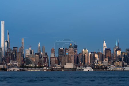 Téléchargez les photos : Gratte-ciel de New York et Hudson River en soirée, front de mer et immeubles de bureaux, centre d'affaires financier. Manhattan midtown skyline buildings in row - en image libre de droit