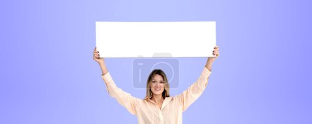 Téléchargez les photos : Heureuse femme souriante tenant un panneau blanc maquette dans les mains, copier l'espace fond violet. Concept de publicité, annonce, vente, marketing et panneau d'affichage - en image libre de droit