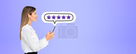 Photo for Side portrait of beautiful young and happy European businesswoman holding smartphone with five star rating above it over purple copy space background. Concept of product and service evaluation - Royalty Free Image