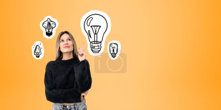 Photo for Dreaming and thinking young woman portrait with index finger point up, light bulbs doodle drawing on orange empty copy space background. Concept of brainstorm, creativity and start up - Royalty Free Image