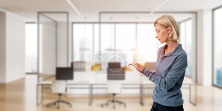 Photo for Young woman finger touch tablet, blurred background of business office coworking loft. Furniture and panoramic window. Concept of workplace, career and occupation - Royalty Free Image