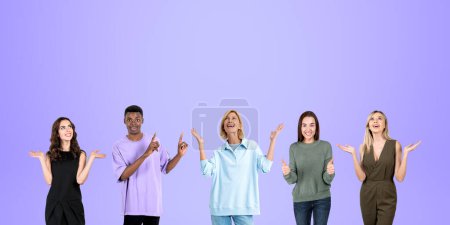 Téléchargez les photos : Portrait de quatre femmes heureuses et d'un homme célébrant la victoire avec les mains levées sur fond violet. Concept de succès et de travail d'équipe - en image libre de droit