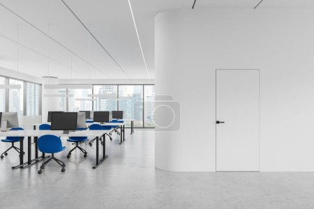 Foto de Acogedor interior de oficina con sillas y escritorio en fila, piso de hormigón ligero. Sala de coworking con puerta invisible, ordenadores PC y ventana panorámica de los rascacielos de Nueva York. Renderizado 3D - Imagen libre de derechos