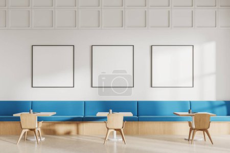 Foto de Interior del restaurante blanco con sillas y mesa, suelo de hormigón. Sofá azul a lo largo de la pared, zona de comer minimalista con tres carteles de lona simulados en fila. Renderizado 3D - Imagen libre de derechos