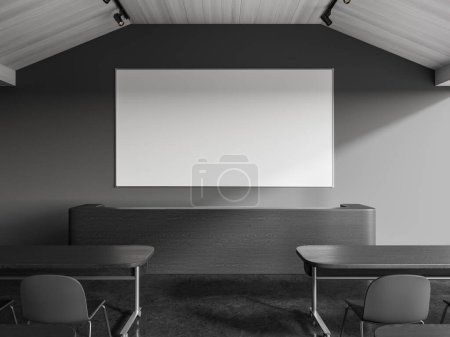 Téléchargez les photos : Intérieur de la classe de collège élégant avec des murs gris, sol en béton, tables confortables avec des chaises grises et tableau blanc vierge suspendu au-dessus de la table des conférenciers. Rendu 3d - en image libre de droit