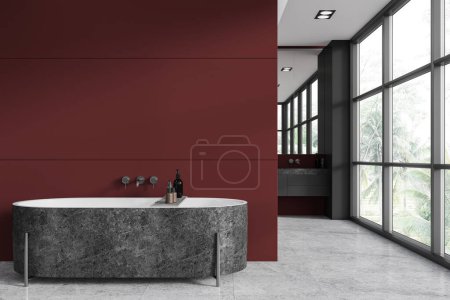Téléchargez les photos : Intérieur de la salle de bain élégante avec des murs rouges et gris, sol en béton, baignoire grise confortable et lavabo avec grand miroir en arrière-plan rendu 3d - en image libre de droit