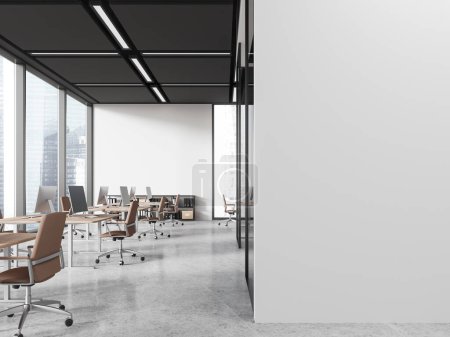 Foto de Interior de la moderna oficina de espacio abierto con paredes blancas, piso de hormigón, fila de escritorios de ordenador con sillas marrones y pared de espacio de copia a la derecha. renderizado 3d - Imagen libre de derechos