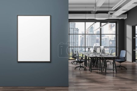 Foto de Interior de la oficina elegante espacio abierto con paredes grises y azules, piso de madera y fila de mesas de ordenador con sillas y la maqueta vertical de póster. renderizado 3d - Imagen libre de derechos