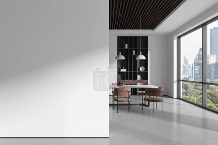 Téléchargez les photos : Intérieur de la salle à manger moderne avec murs blancs, sol en béton, longue table à manger avec chaises brunes, bibliothèque et mur d'espace de copie sur la gauche. Rendu 3d - en image libre de droit