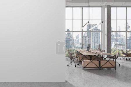 Téléchargez les photos : Intérieur du bureau moderne à aire ouverte avec murs blancs, sol en béton, rangée de bureaux informatiques en bois et mur maquette sur la gauche. Rendu 3d - en image libre de droit