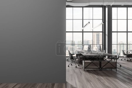 Téléchargez les photos : Intérieur d'un élégant bureau à aire ouverte avec des murs gris, du parquet, une rangée de bureaux en bois sombre et un mur maquette à gauche. Rendu 3d - en image libre de droit