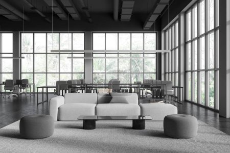 Foto de Oscuro interior de oficina de negocios con zona de relax y coworking. Sofá modular gris con mesa de centro, escritorio compartido y sillones en fila, ventana panorámica en los trópicos. Renderizado 3D - Imagen libre de derechos