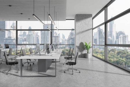 Photo for Industrial office interior with pc computers and shared desk in row, grey concrete floor. Stylish coworking space with panoramic window on Bangkok skyscrapers. 3D rendering - Royalty Free Image