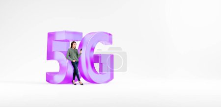 Photo for Portrait of young woman holding smartphone and standing near big 5G sign over white copy space background. Concept of technology, communication and internet connection, telecommunication - Royalty Free Image