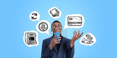 Foto de Feliz joven afroamericano usando un teléfono inteligente de pie sobre un fondo azul con iconos de devolución de efectivo dibujados en él. Concepto de banca en línea, chashback y reembolso - Imagen libre de derechos