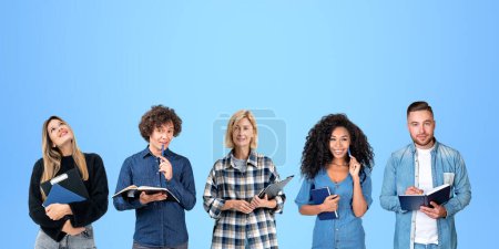 Photo for Group of diverse college or university students holding notebooks and standing in row over blue background. Concept of brainstorming and education - Royalty Free Image