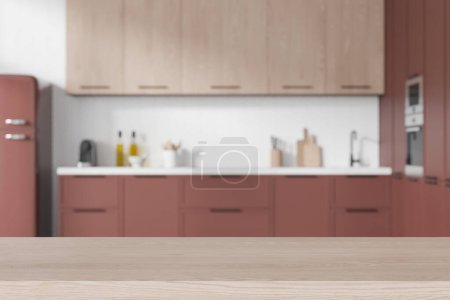 Téléchargez les photos : Table de placement de produits en bois debout dans une cuisine moderne floue avec des murs blancs et des armoires roses confortables et un réfrigérateur. Espace de copie. Rendu 3d - en image libre de droit
