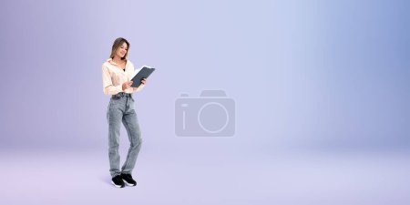 Photo for Smiling young woman full length reading a paper document, clipboard in hands on empty copy space purple background. Concept of portfolio, cv, start up plan and contract - Royalty Free Image