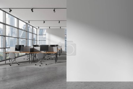 Foto de Interior de la moderna oficina de espacio abierto con paredes blancas, suelo de moqueta y filas de escritorios de ordenador con sillas grises de pie cerca de la ventana panorámica con paisaje urbano. Copiar pared espacial. renderizado 3d - Imagen libre de derechos