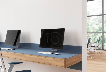 Téléchargez les photos : Vue d'angle intérieur de bureau avec moniteurs PC sur longue table, zone de coworking avec cloison, fauteuils en rangée sur plancher de bois franc. Fenêtre panoramique sur les tropiques. rendu 3D - en image libre de droit