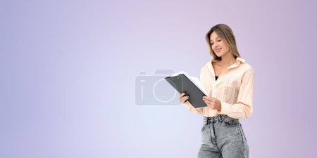 Foto de Mujer feliz leyendo un documento en papel, sosteniendo el portapapeles en las manos en el espacio de copia vacío fondo púrpura. Concepto de cartera, cv, plan de puesta en marcha y contrato - Imagen libre de derechos