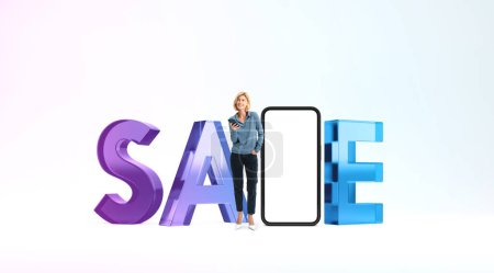 Foto de Joven mujer europea con teléfono inteligente de pie cerca de letrero de gran venta con pantalla de teléfono simulada sobre fondo blanco. Concepto de compras en línea - Imagen libre de derechos