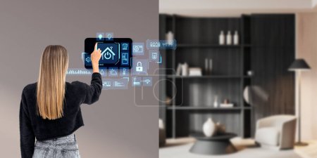Photo for Rear view of woman finger touch tablet on wall in living room interior. Digital computer for home management, diverse icons hologram. Concept of technologies, remote control and indicators - Royalty Free Image