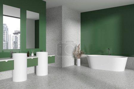 Téléchargez les photos : Coin de salle de bain élégante avec murs verts, sol en béton, baignoire blanche confortable et double lavabo avec deux miroirs verticaux. Rendu 3d - en image libre de droit