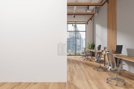 Téléchargez les photos : Intérieur du bureau moderne à aire ouverte avec des murs gris et blancs, sol en bois et rangées de bureaux d'ordinateur avec des chaises beige. Copier le mur d'espace sur la gauche. Rendu 3d - en image libre de droit