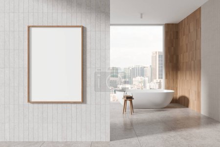 Foto de Interior de baño moderno con paredes blancas y de madera, suelo de baldosas, cómoda bañera blanca y marco de póster maqueta vertical. renderizado 3d - Imagen libre de derechos