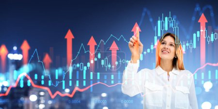 Photo for Smiling businesswoman finger touch forex stock market hologram, growing arrows and candlesticks. Blurred city skyscrapers. Concept of financial analysis and money investment - Royalty Free Image