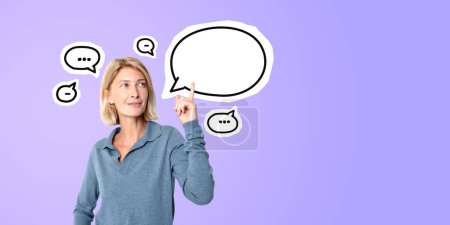 Photo for Portrait of cheerful young woman pointing up and standing over purple background with speech bubble. Concept of communication and bright idea - Royalty Free Image