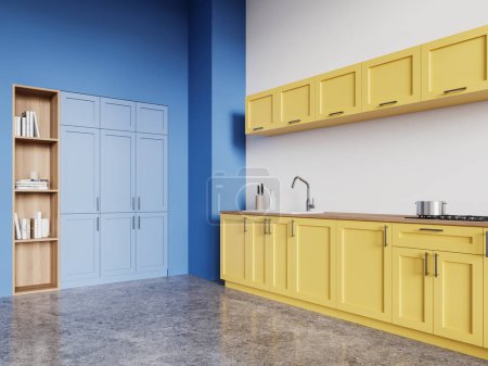Foto de Vista de esquina del interior de la cocina del hogar amarillo y azul con armario de cocina, utensilios de cocina en el mostrador. Estante con libros sobre suelo de hormigón. Diseño coloreado en apartamento moderno. Renderizado 3D - Imagen libre de derechos