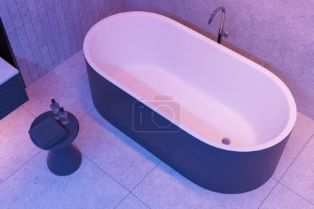 Foto de Vista superior del elegante interior del baño del hotel con bañera y mesa auxiliar, suelo de granito azulejo. Esquina de baño en apartamento moderno con iluminación de neón. Renderizado 3D - Imagen libre de derechos