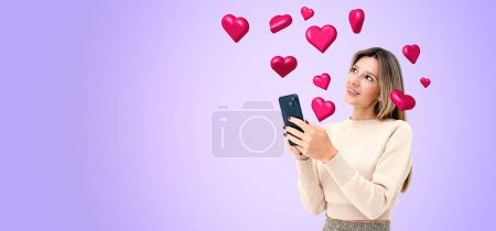 Portrait of cheerful young woman standing with smartphone with social media icons over purple copy space background. Concept of online communication