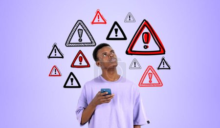 Foto de Hombre africano reflexivo con teléfono inteligente en la mano. Señales de advertencia rojas dibujan en fila sobre fondo púrpura. Concepto de amenaza en línea, seguridad de datos y antivirus - Imagen libre de derechos