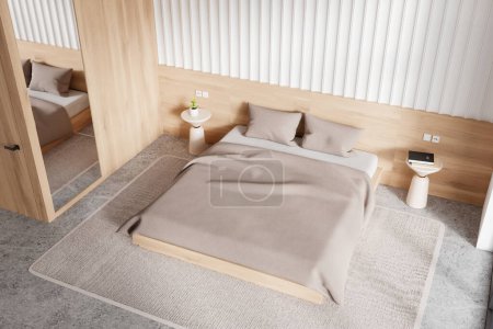Vue de dessus de l'intérieur de la chambre moderne avec des murs blancs et en bois, sol en béton, lit king size confortable et deux tables de chevet rondes. Rendu 3d